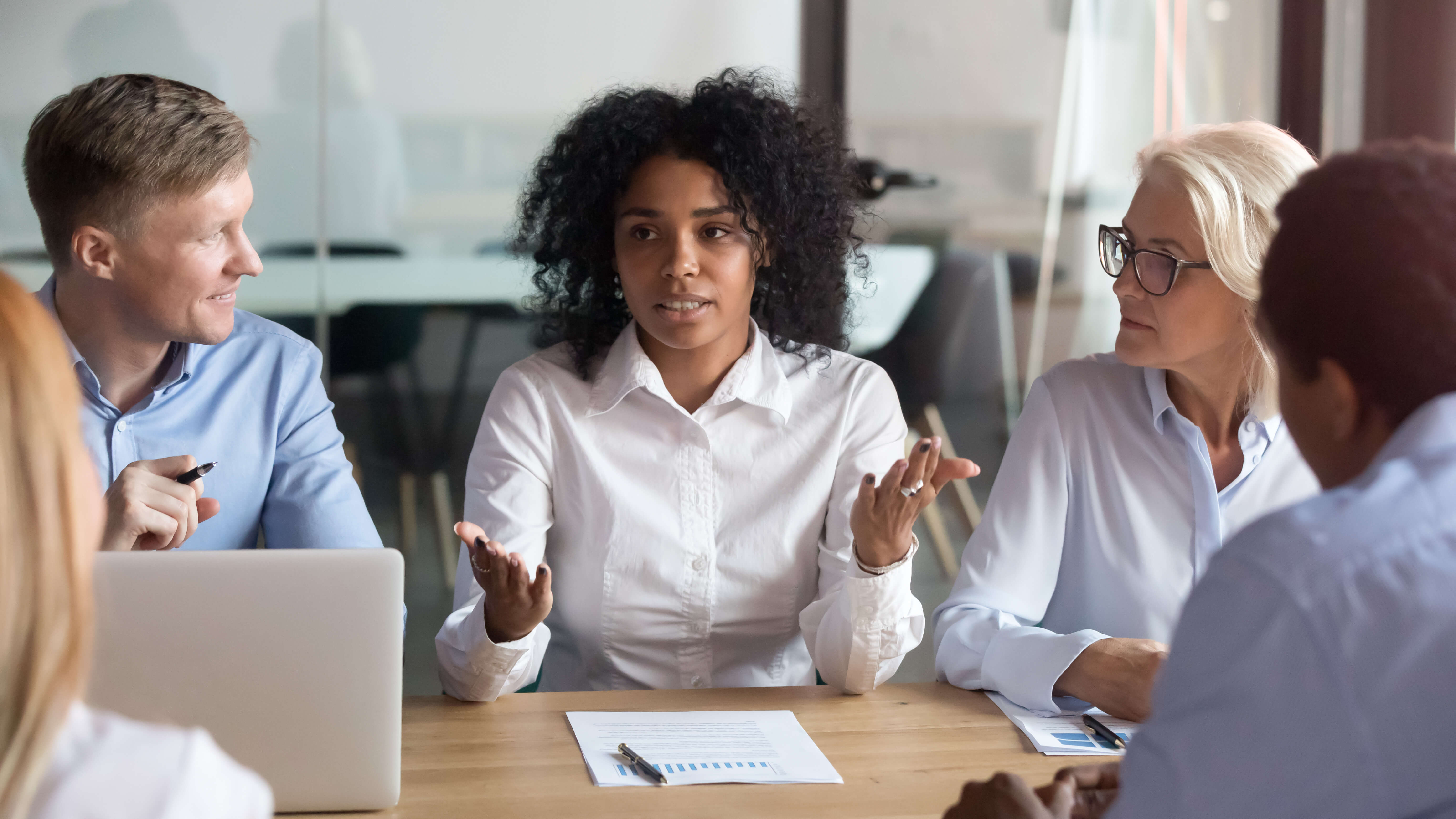 Team meeting with woman explaining to four colleagues